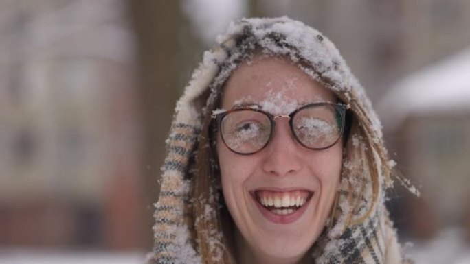 微笑而快乐的年轻女子，脸上和眼镜上有雪