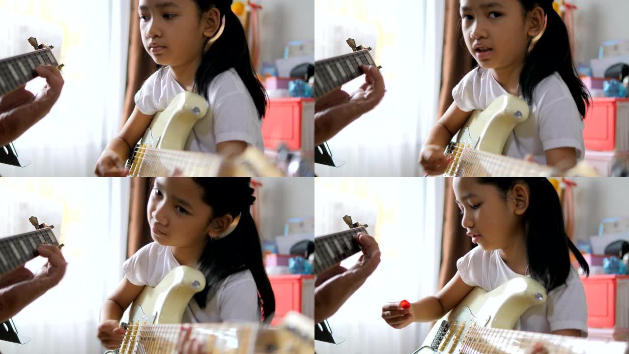 父亲教亚洲小女孩用电吉他学基本吉他初学者乐器自学在家学习，快乐家庭弹吉他