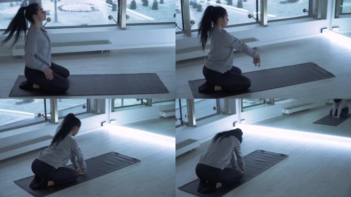 年轻女子在健身房的垫子上做瑜伽