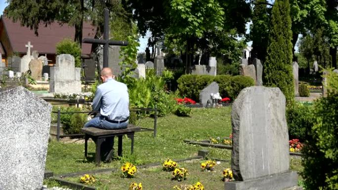 哀悼丈夫的男人坐在墓地妻子坟墓附近的长凳上。4K