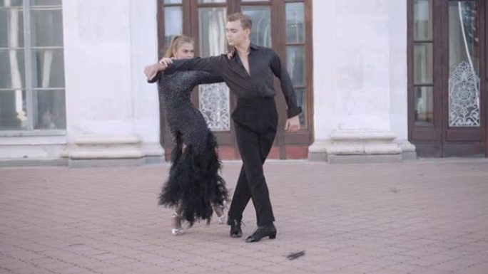 自信的夫妇在城市表演帕索多布尔的镜头。熟练的才华横溢的年轻高加索芭蕾舞演员在户外跳舞的肖像。拉丁交际