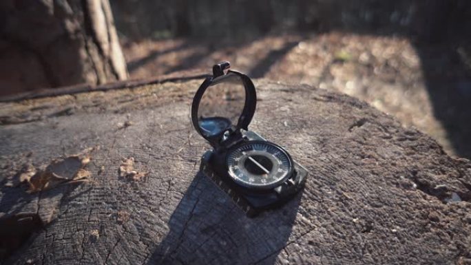 主题是旅游和科技。特写导航罗盘黑色磁针躺在森林的树桩上晴朗的天气。
