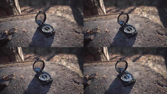 主题是旅游和科技。特写导航罗盘黑色磁针躺在森林的树桩上晴朗的天气。
