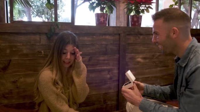 一个男人在咖啡店里向女友提供订婚戒指，但她拒绝了他
