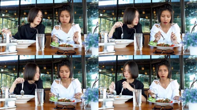 两个可爱的亚洲女孩在咖啡馆/餐厅使用移动智能手机