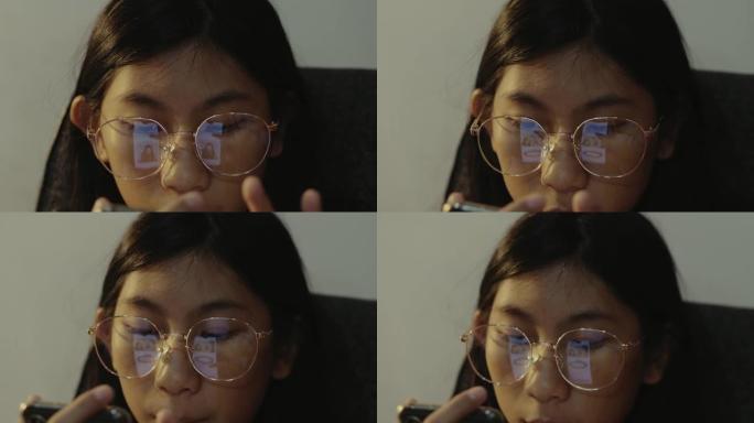 亚洲女孩戴着眼镜使用智能手机在晚上在家，生活方式概念。