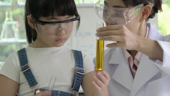 科学家的女人和小女孩正在试验化学物质化合物和吸收液体的试管。科学、测试开发和实验室行业的概念。