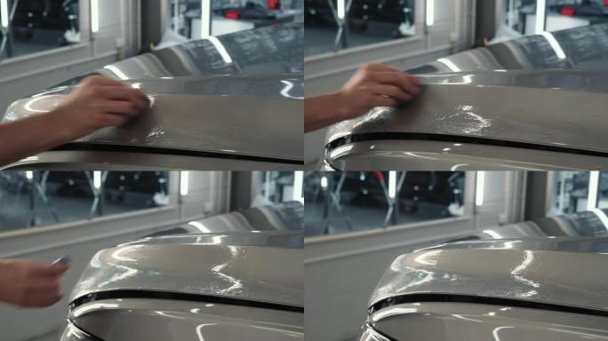 工人在汽车上施加保护层或涂层之前，用蓝色粘土手工清洁车身以进行清洁。汽车细节概念