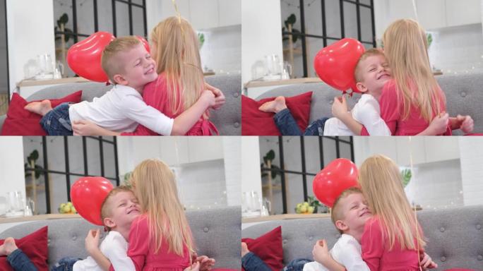 小男孩抱着心爱的女孩在家用红色心形气球庆祝情人节。慢动作