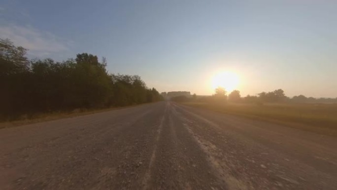 夏季日出时，汽车在风景秀丽的树木周围的道路上快速行驶。在农村公路上行驶时的视点镜头。