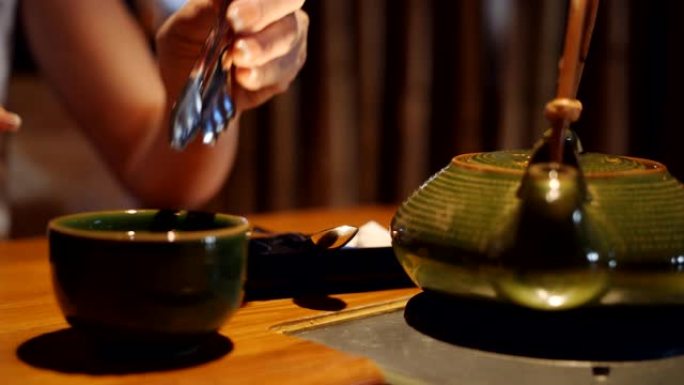 女人拿特殊的钳子方糖，放在餐厅的一杯茶中。