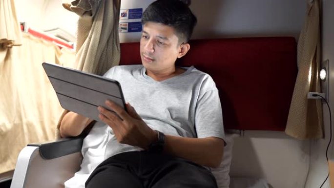 亚洲男子在火车上使用平板电脑，触摸板