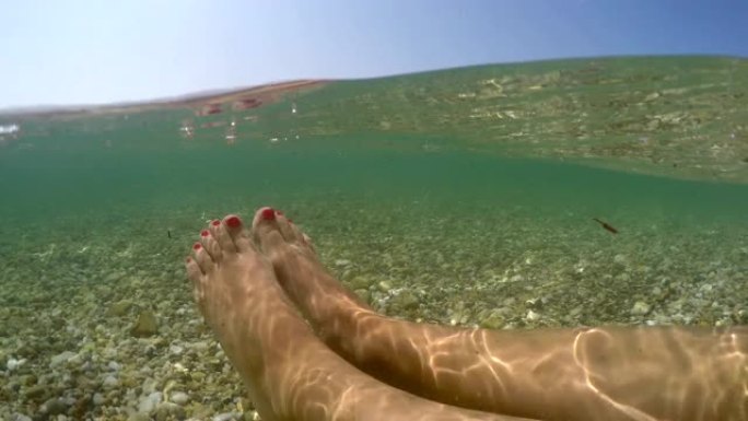 女性脚在海水浅水中放松漂浮，暑假概念，半水下视图gopro圆顶拍摄