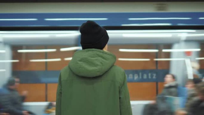 一名年轻女子站在地铁站，而一列地铁列车在她面前经过。