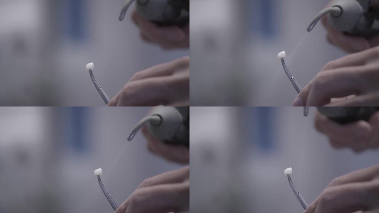 牙科技师在牙科实验室使用压缩空气blaster抛光人造陶瓷牙齿。专业拿着假牙，用空气冲击波抛光