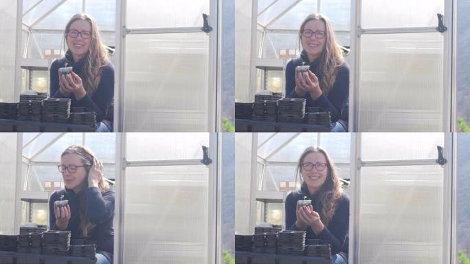 微笑的成熟女人在温室前抱着番茄苗