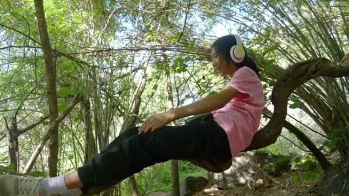 快乐的亚洲女孩在竹林的树枝上放松和乐趣，生活方式的概念。