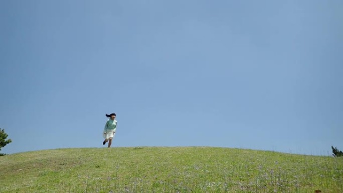 在蓝天下跑下山坡的日本女孩