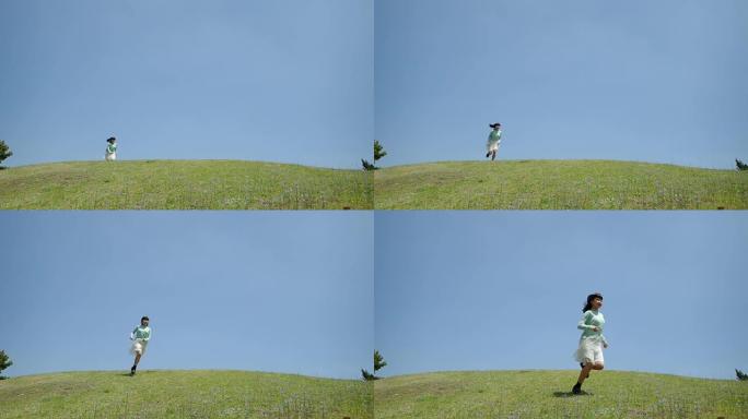 在蓝天下跑下山坡的日本女孩