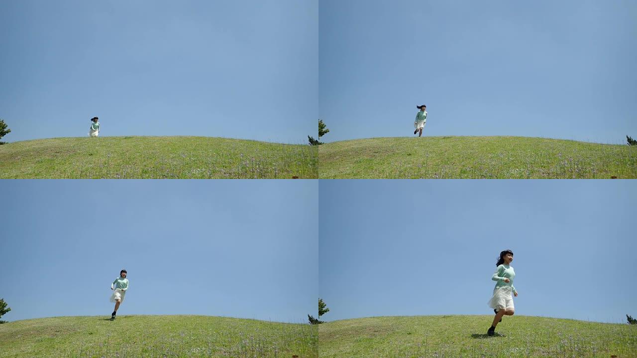 在蓝天下跑下山坡的日本女孩
