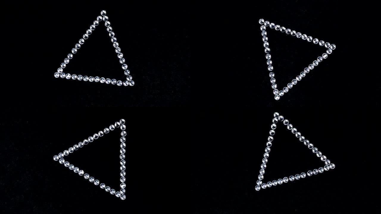 在黑色织物上旋转由银色水钻制成的三角形，该三角形象征着完成。