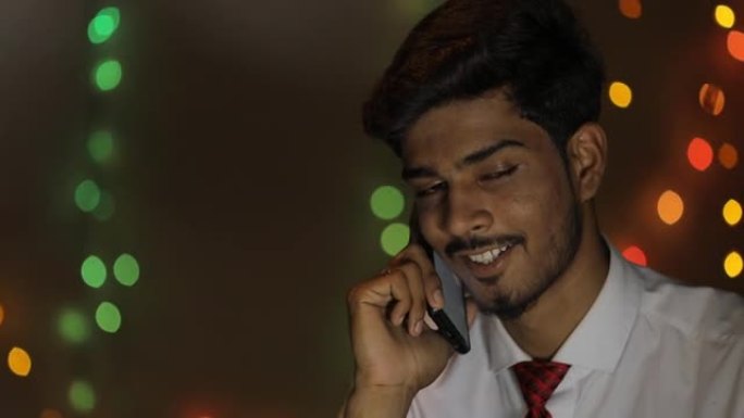 年轻的印度男子在家中在照明背景下使用笔记本电脑