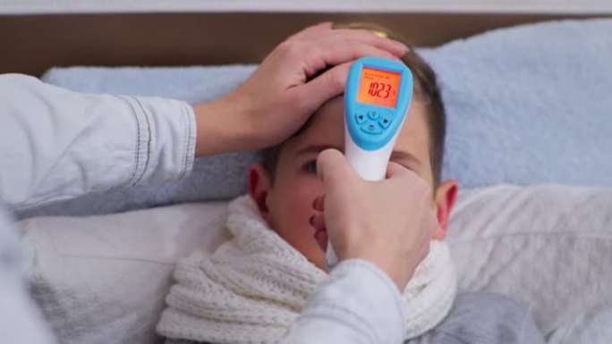 疾病和感冒，健康状况不佳的小男孩，母亲测量华氏温度高，非接触式温度计特写