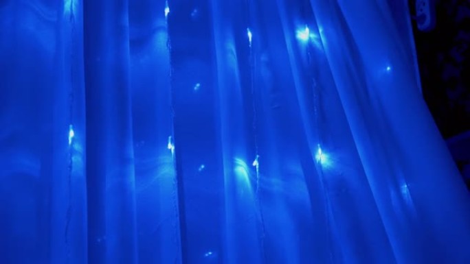 窗帘上许多闪烁的蓝色发光二极管灯的圣诞花环