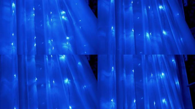 窗帘上许多闪烁的蓝色发光二极管灯的圣诞花环