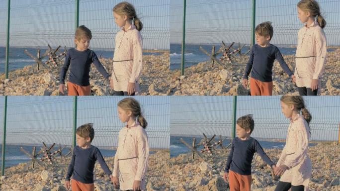 两个贫穷的难民儿童站在战争冲突地区的海边。男孩和女孩等待被救出