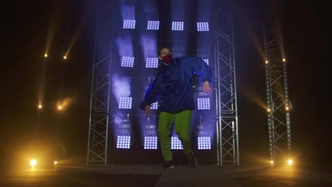 才华横溢的年轻嘻哈舞者的剪影。嘻哈街舞在黑暗工作室的舞台上，有烟雾和霓虹灯。动态照明效果。创造技能。