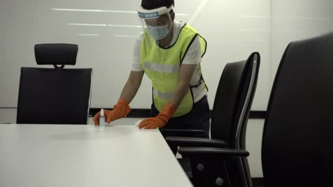冠状病毒COVID-19预防清洁人员在公共会议室把手表面用杀菌消毒液擦拭清洁桌子。