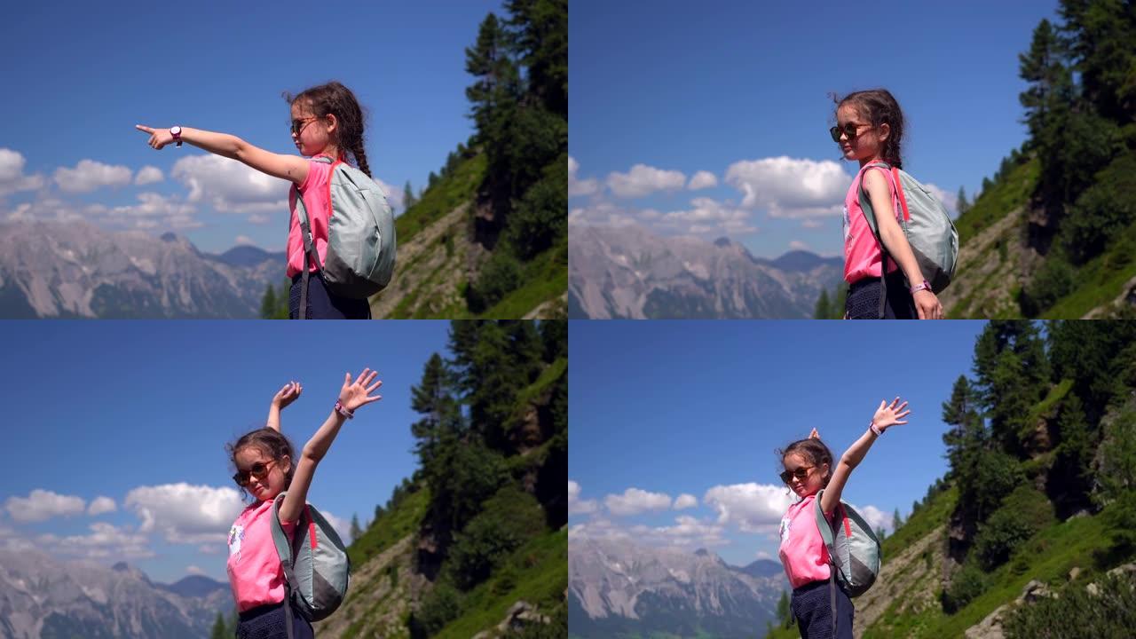 女孩在奥地利阿尔卑斯山美丽的夏日徒步旅行，在岩石上休息，欣赏山峰的壮丽景色。带着孩子积极的家庭度假休
