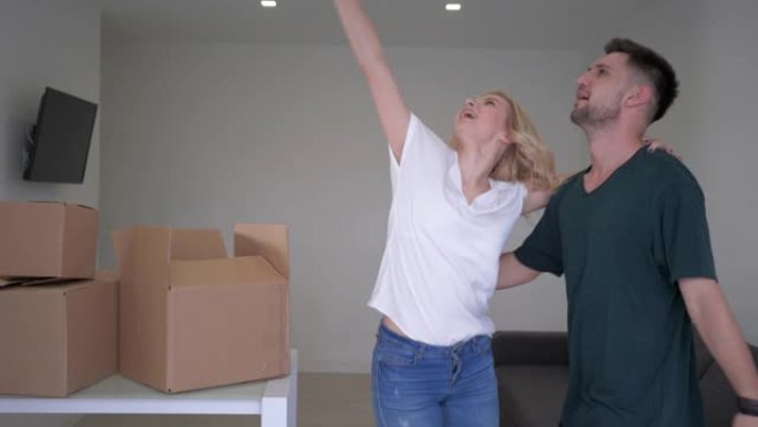 快乐的乔迁，快乐的年轻夫妇新房主有趣的跳舞，并享受带盒子的新公寓