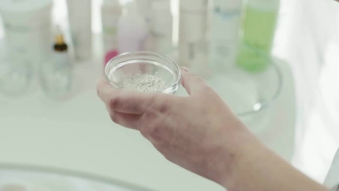 女人的手在碗里搅拌化妆品面膜。特写。
