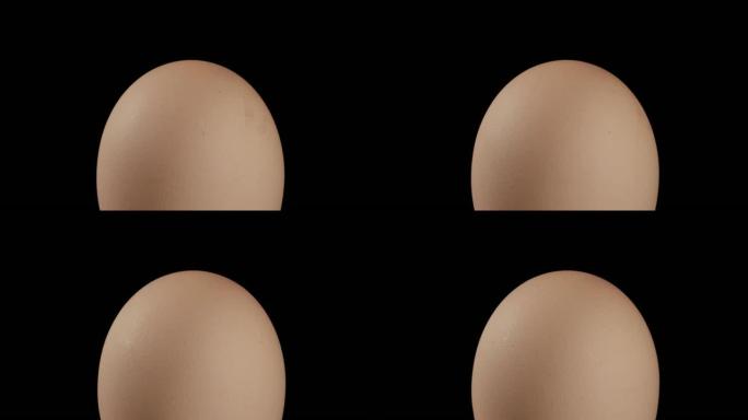 特写，整个棕色鸡蛋在黑色背景上的旋转表面上，直立位置
