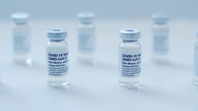护士手持Covid-19疫苗小瓶和注射器，背景清晰。概念:预防冠状病毒。