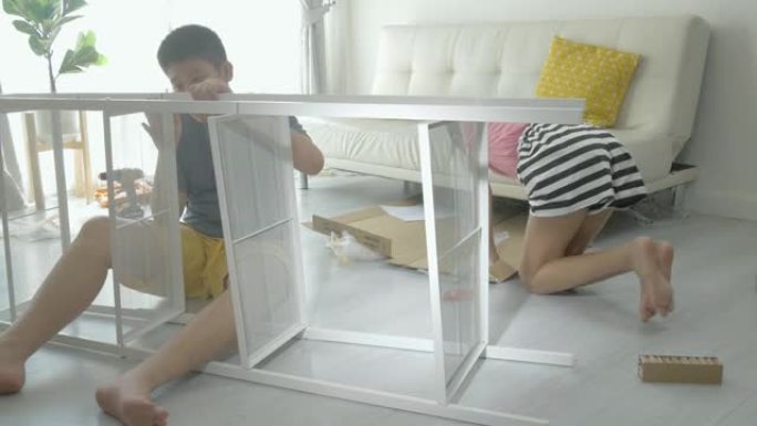 亚洲孩子试图将他们的新白色架子组装在一起，这是从网上购物，生活方式概念中购买的。