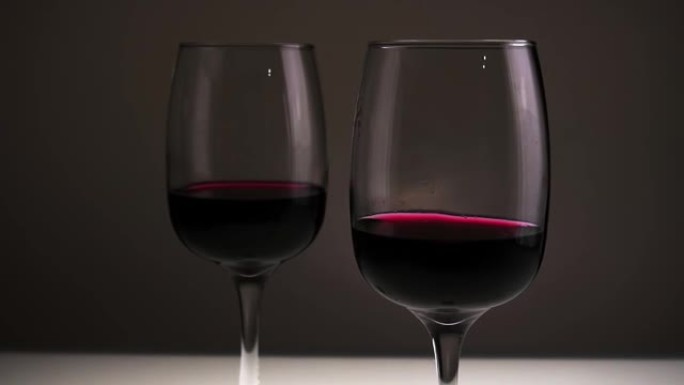 红酒，两杯在黑暗背景下的桌子上。慢动作。