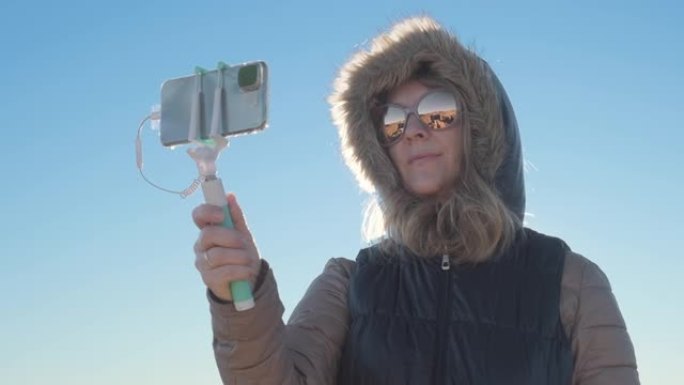 一个漂亮的女人在寒冷多风的天气里自拍并通过社交媒体分享的特写镜头。