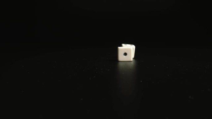 白色骰子落在黑色表面上的特写镜头。掷骰子。