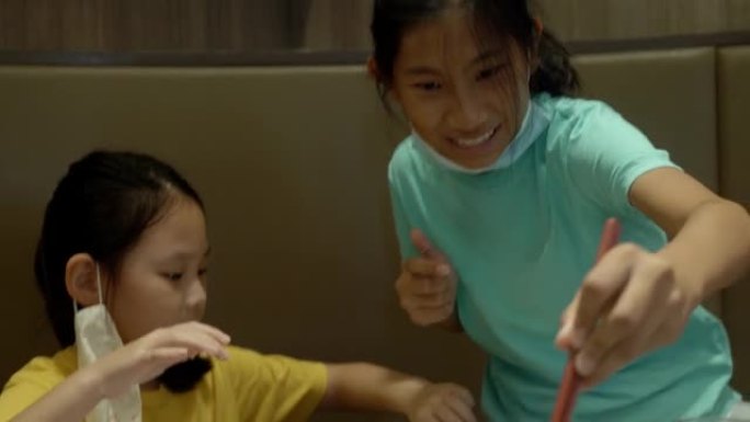 快乐的3个亚洲女孩在餐厅和家人一起吃寿喜烧、烧锅或火锅，生活方式理念。
