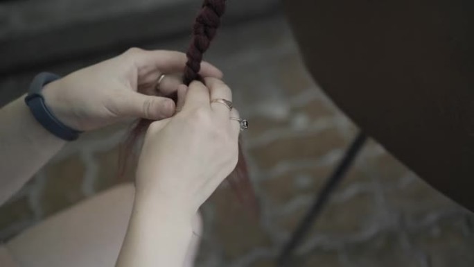 女性的手编着辫子。特写。