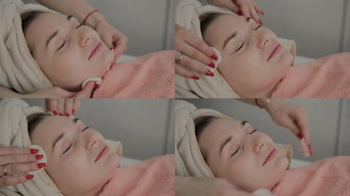 专业美容师用特殊的保湿湿巾摩擦女孩的脸。美容中的新概念