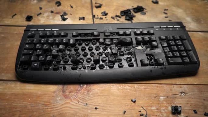 电脑桌上的键盘坏了。封锁。愤怒的男子用锤子砸键盘