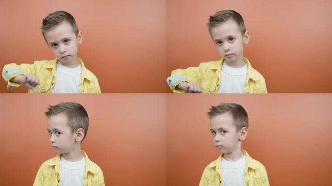 Serioius金发小男孩挥舞着头，在橙色背景上说不，有复制空间。分歧的概念。
