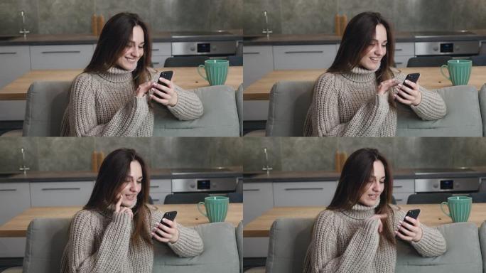 25岁的年轻白人妇女坐在家里的沙发上，穿着一件温暖的毛衣，在现代公寓的智能手机上快速浏览互联网页面。