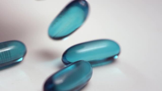 蓝色布洛芬液体凝胶药丸从药瓶中倒出白色表面的宏观特写