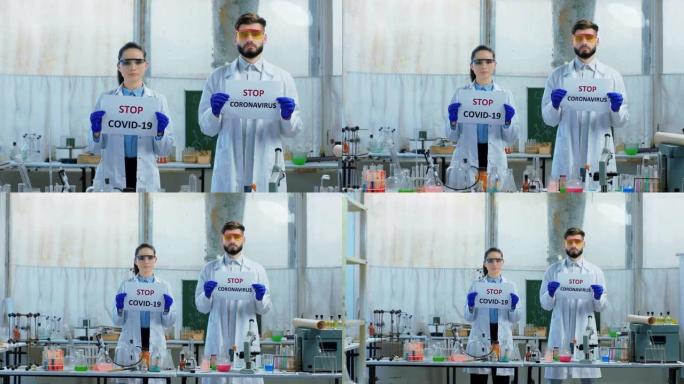 在化学实验室里，两名科学家手持两张“阻止冠状病毒”的海报，直视着镜头