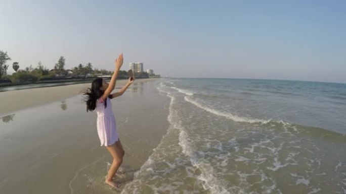 快乐的亚洲女孩自拍自己和视频在阳光明媚的日子里给家人在海滩上打电话，生活方式理念。